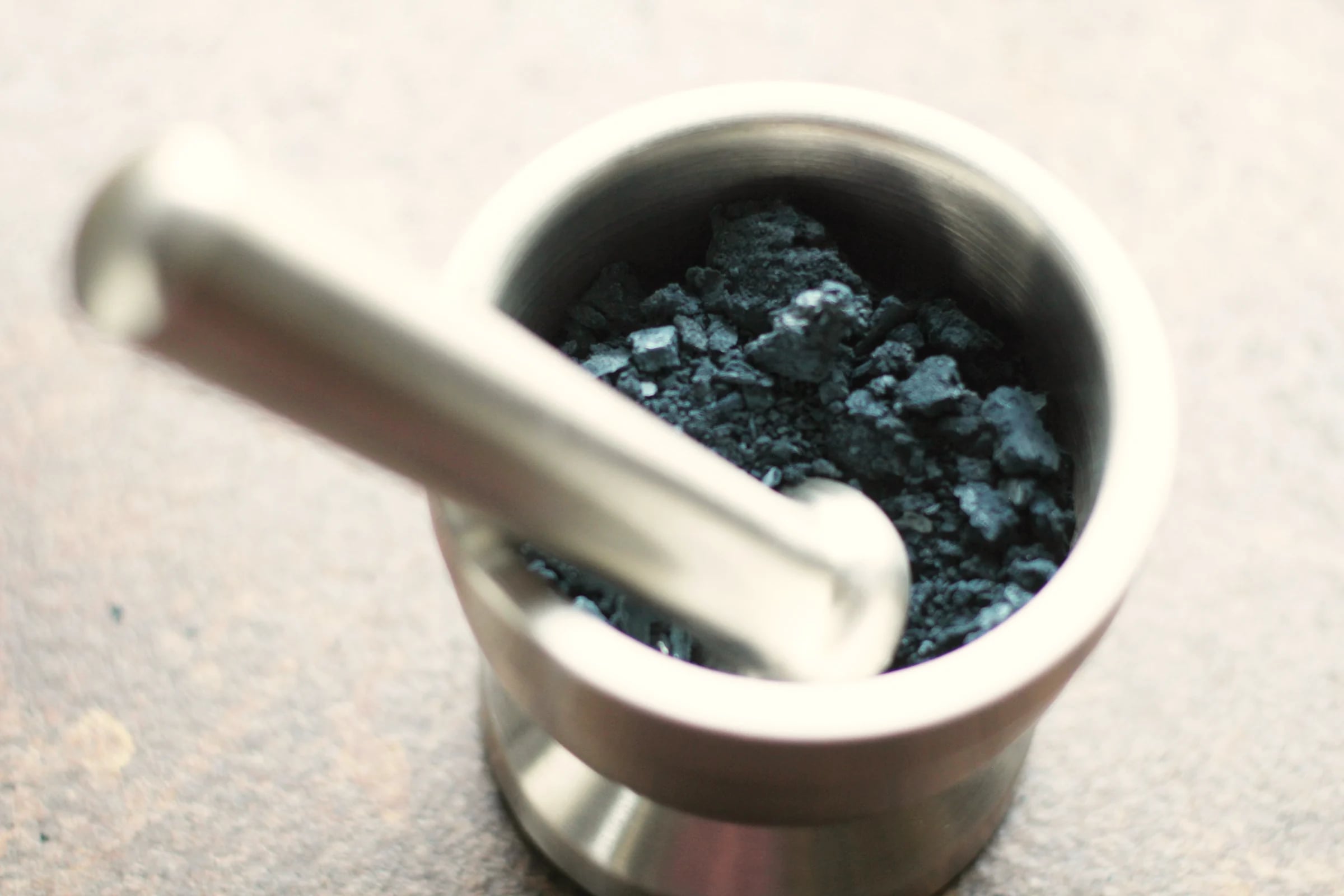 Fine black powder in a steel mortar and pestle