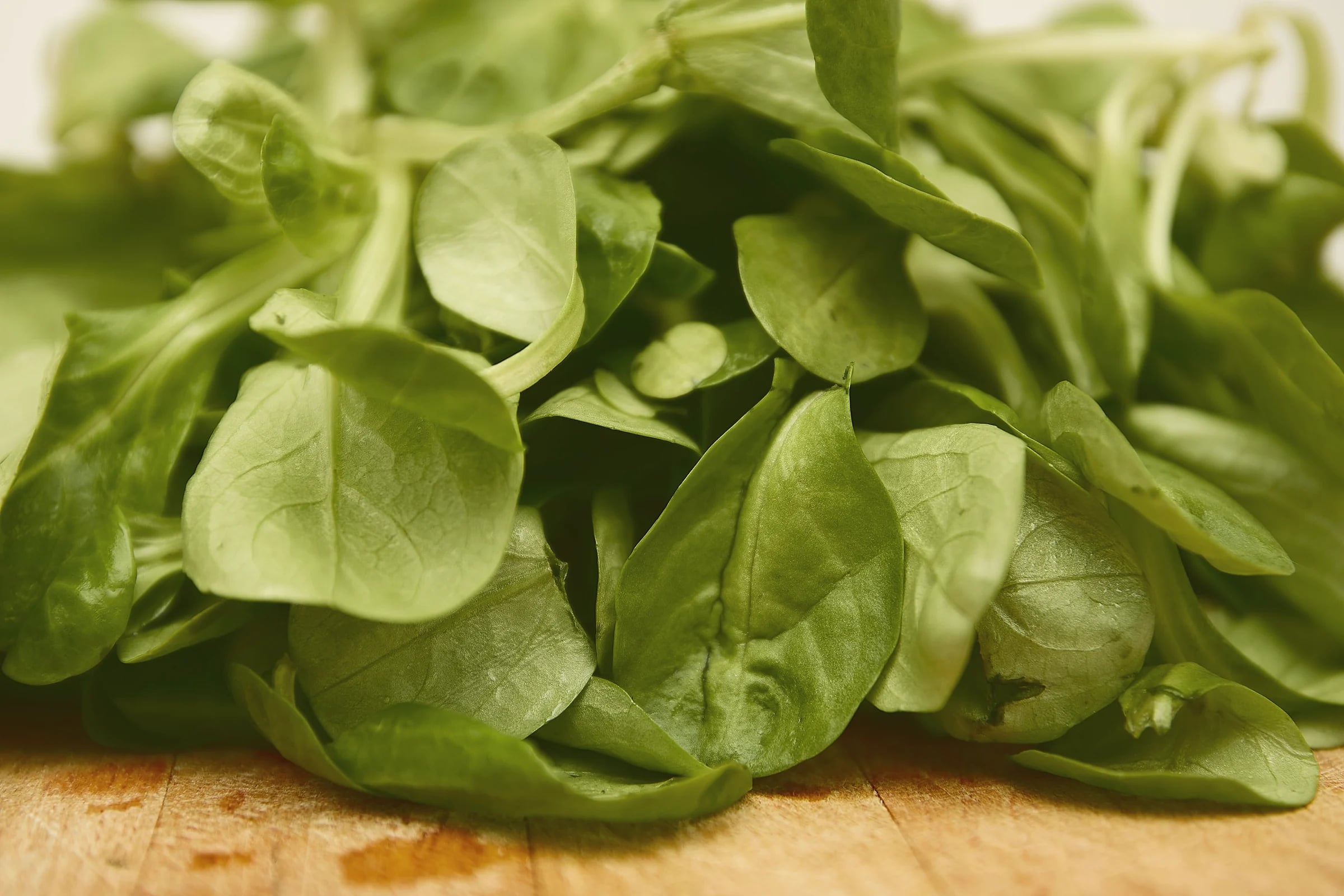 A pile of fresh lamb's lettuce on a wooden board