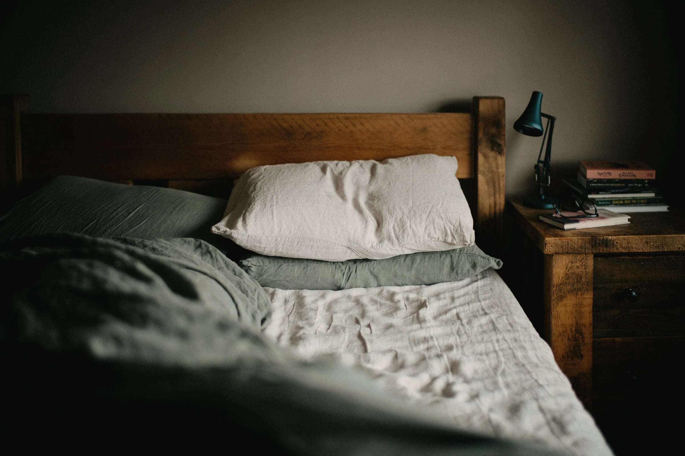 A quiet bedroom with a made bed and a bedside lamp