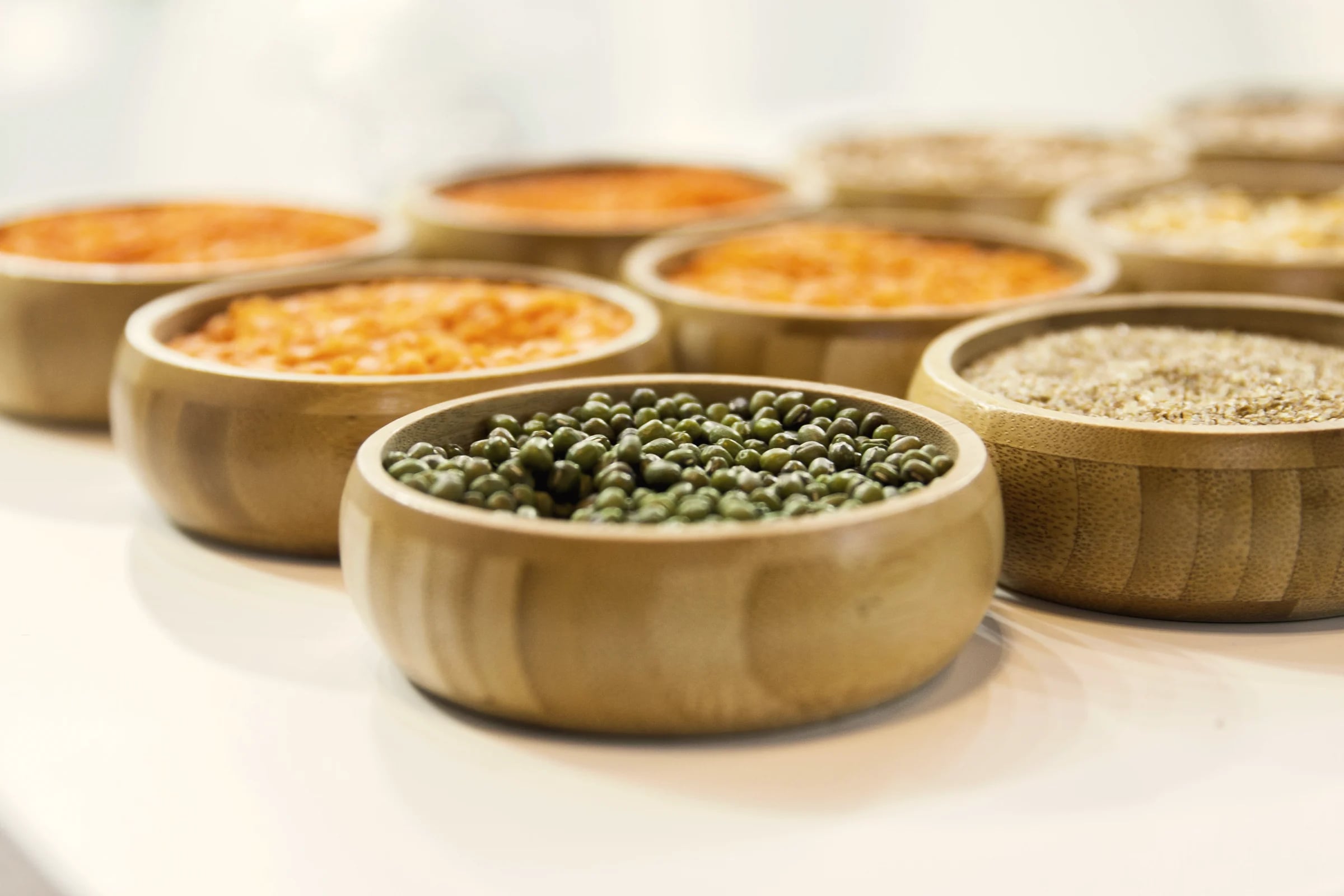 Wooden bowls of lentils, mung beans and grains
