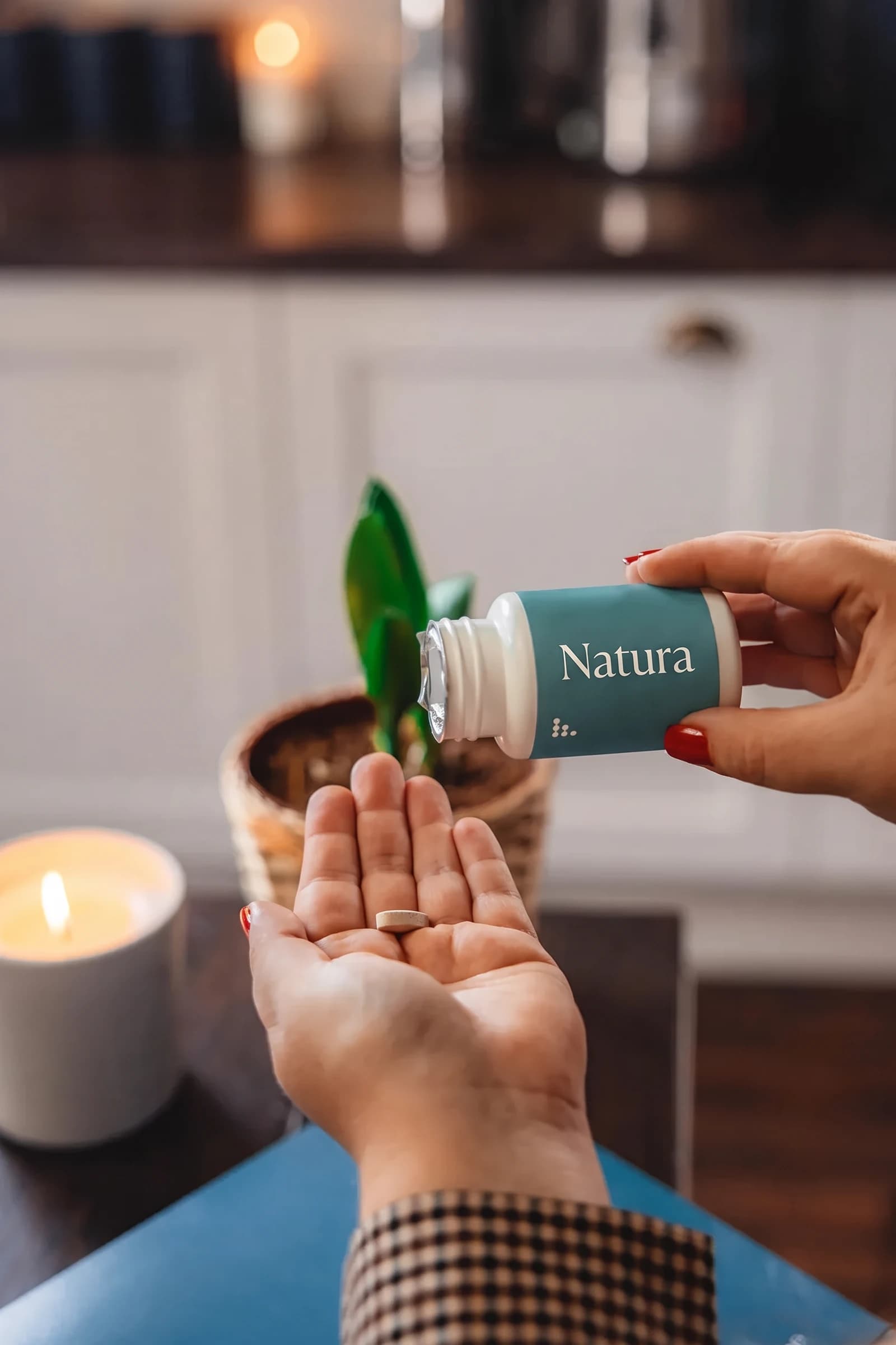 A Natura bottle offered over an open palm by candlelight