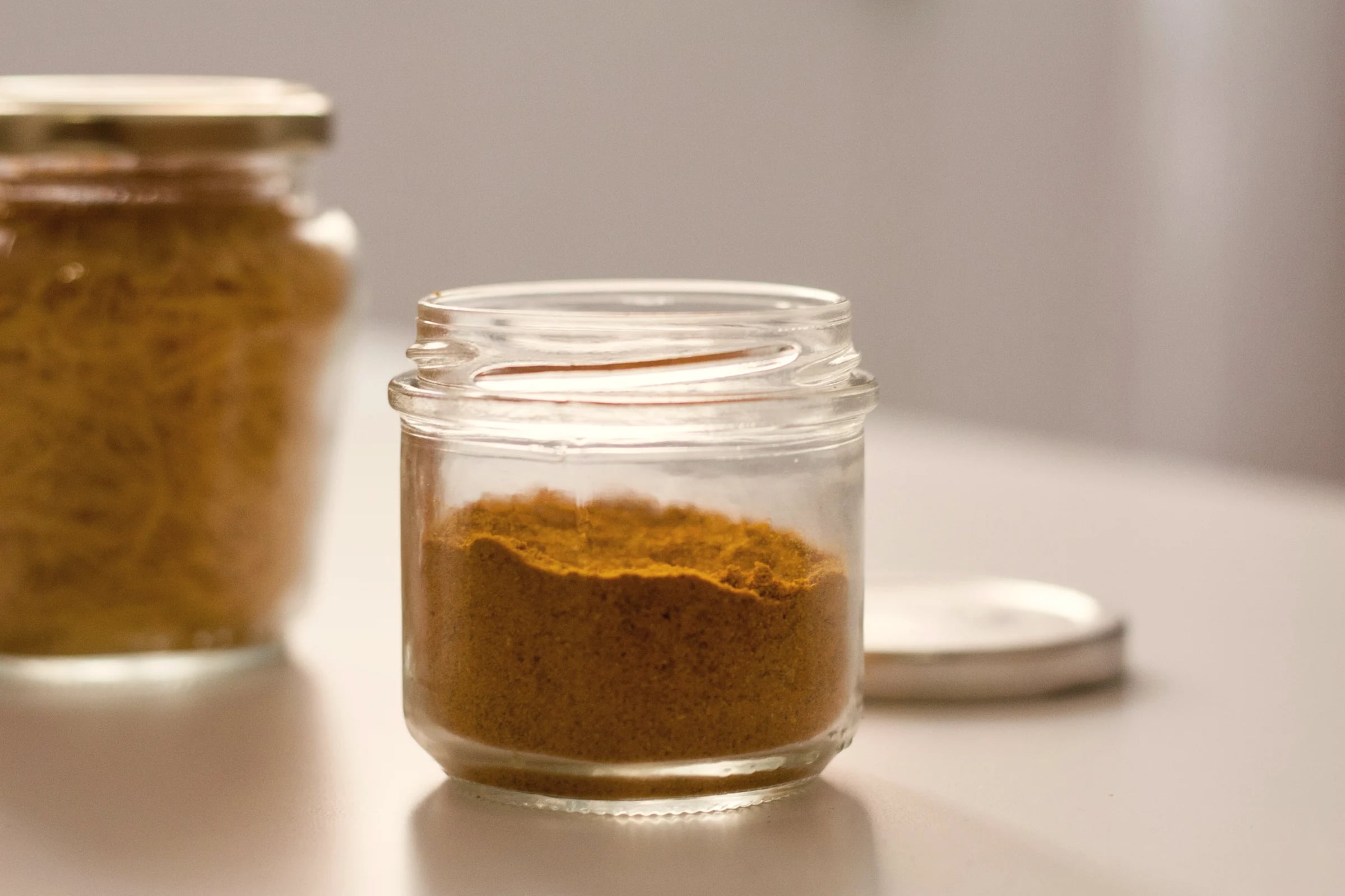 A small glass jar of golden-brown powder on a pale table