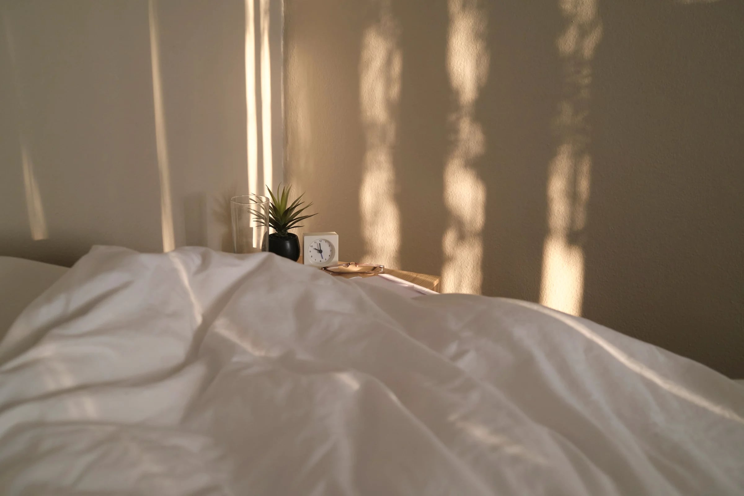 An unmade bed with white linen in evening light