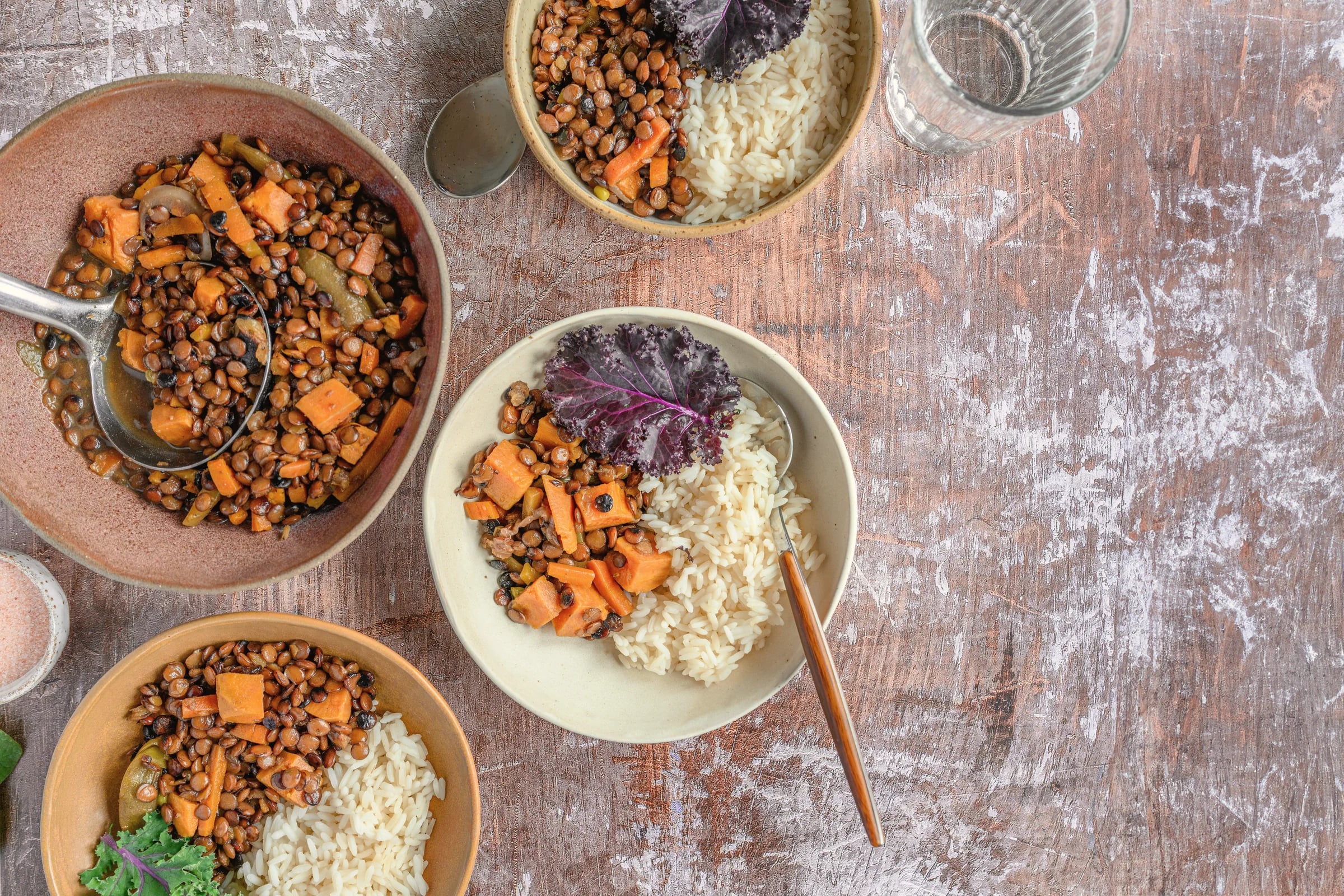 Bowls of lentils, roasted vegetables and grains on a wooden table